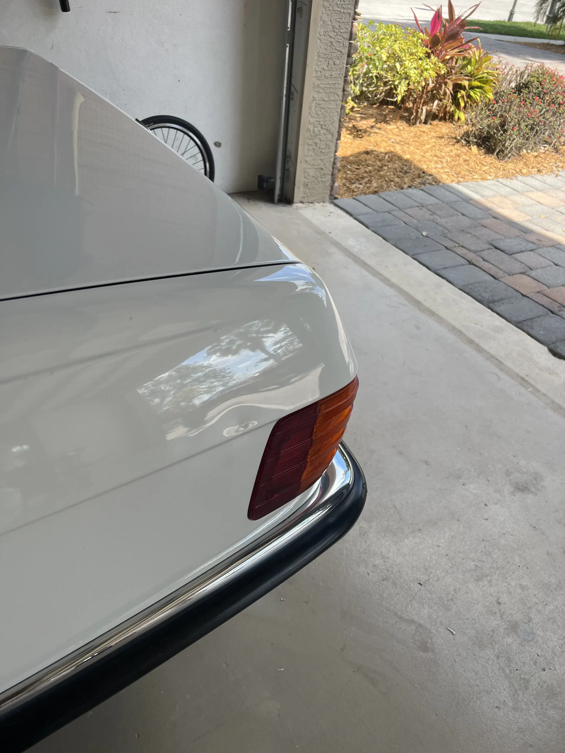 The back of a white Mercedes inside a garage prior to repairs.