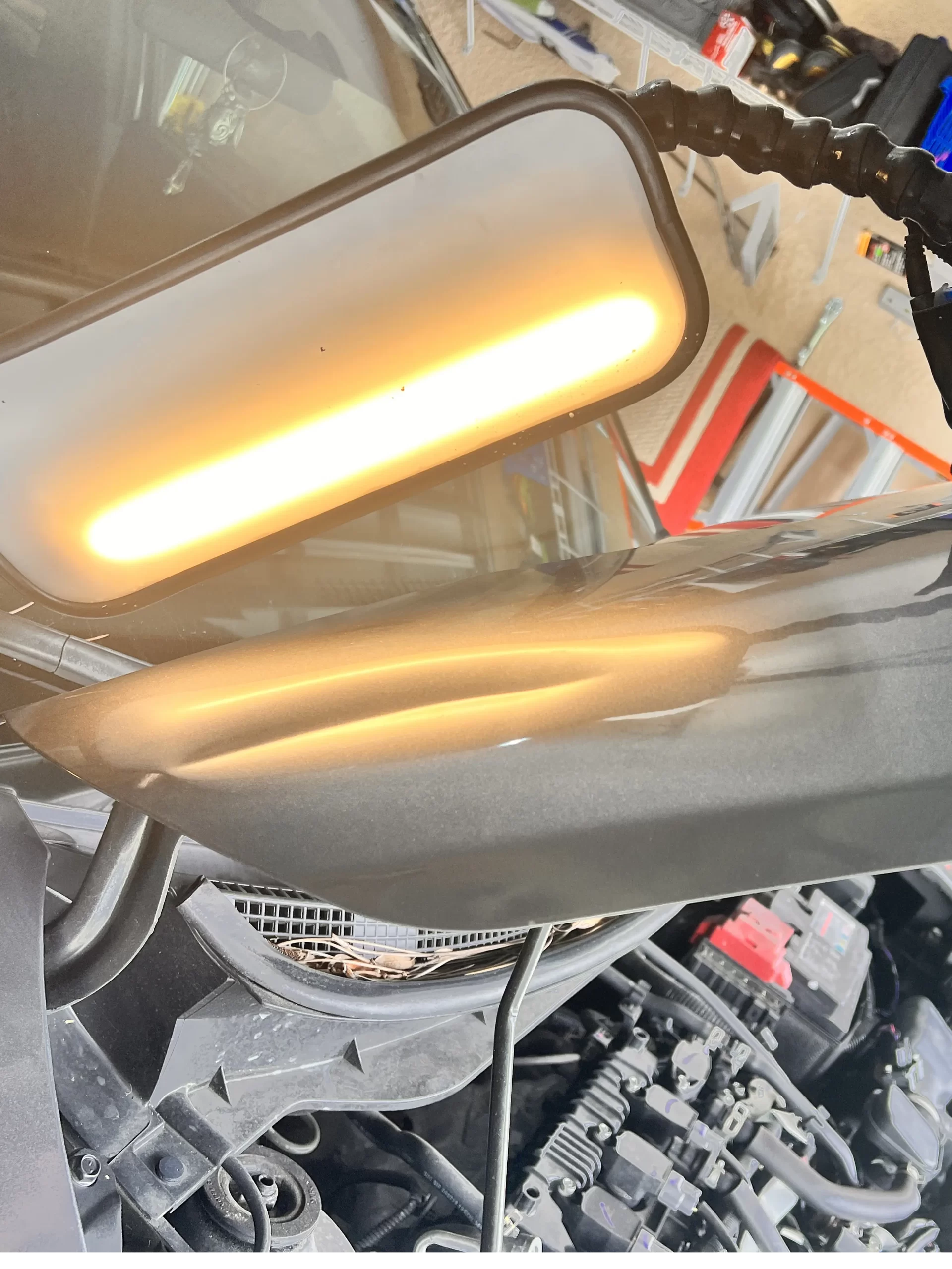 The opened hood of a grey vehicle with its interior shown prior to repairs.