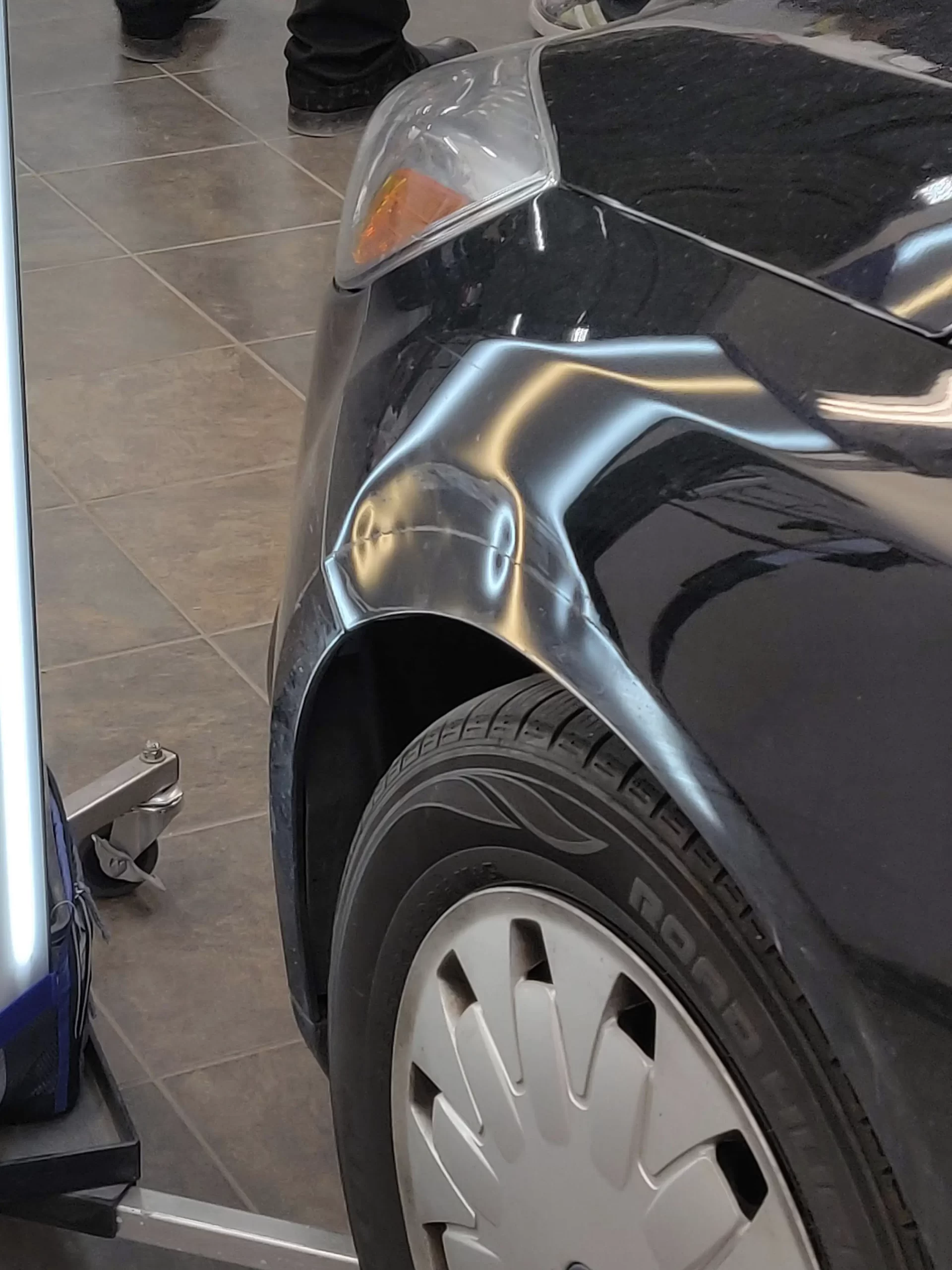 The opened-up hood of a black Ford before repairs.