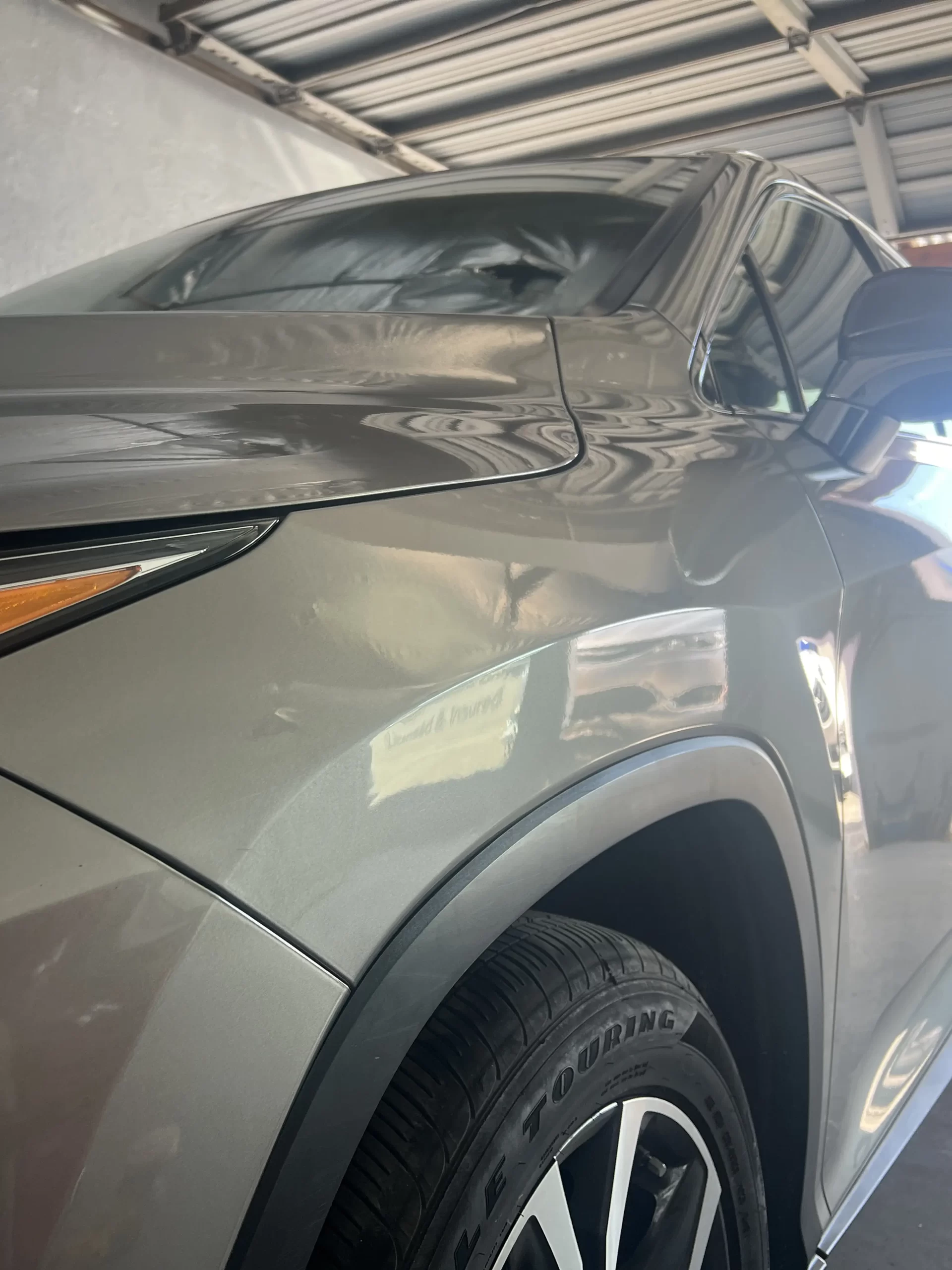 The front, well-polished portion of a grey SUV after repairs.