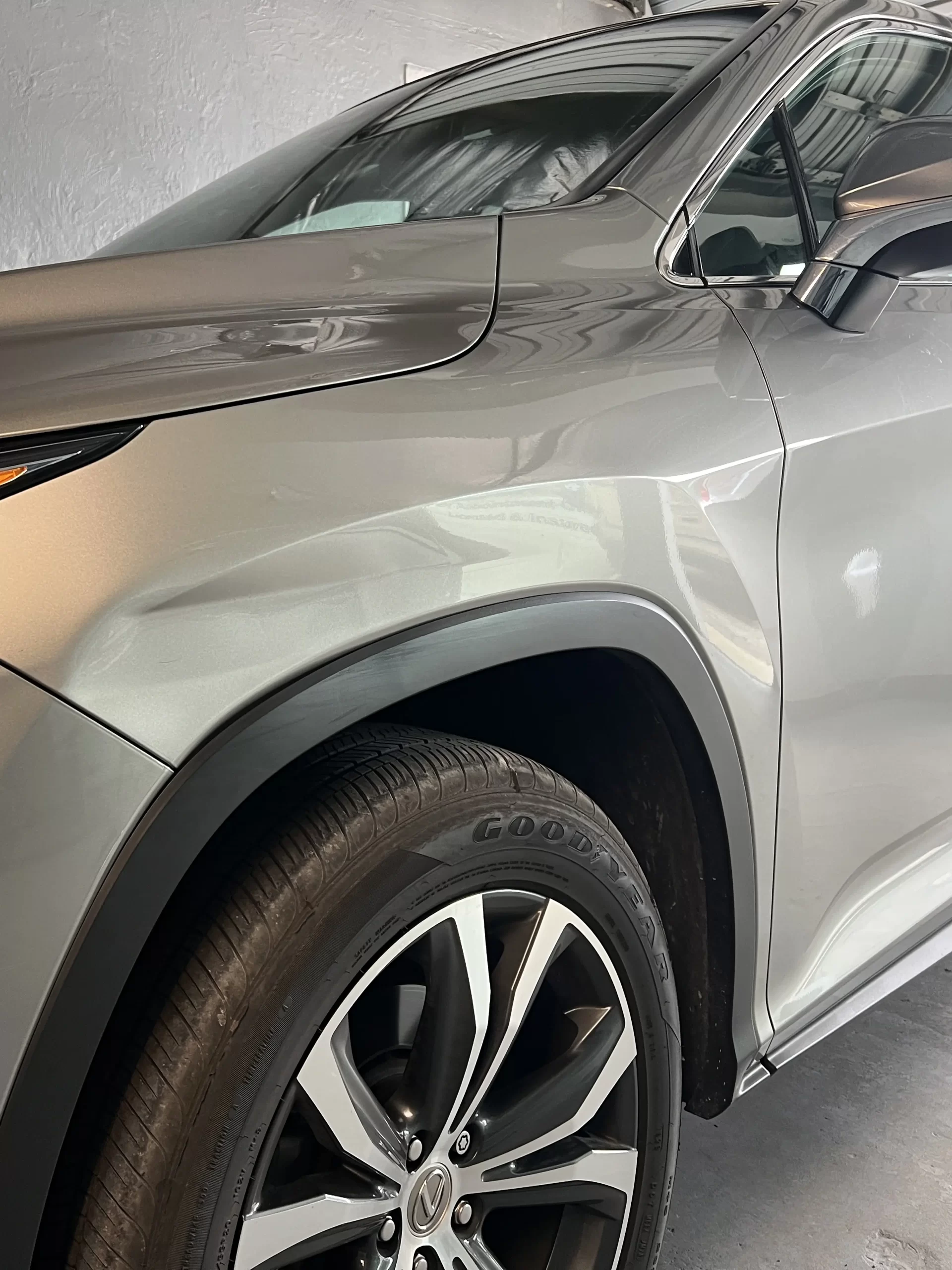 The slightly dented portion of a grey SUV before repairs.